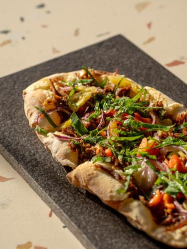 a pizza sitting on top of a black cutting board at Novotel Istanbul Bosphorus Hotel in Istanbul