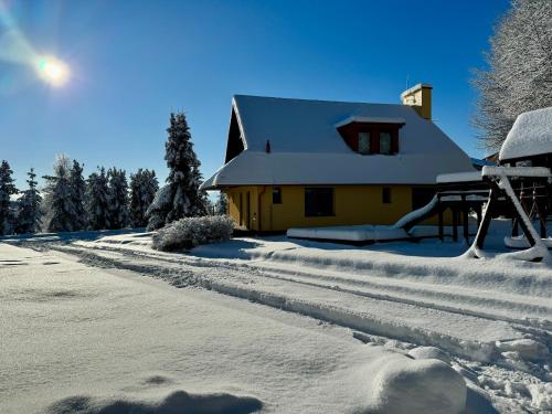 a house covered in snow next to a road at Domček pod lesom in Vysoké Tatry