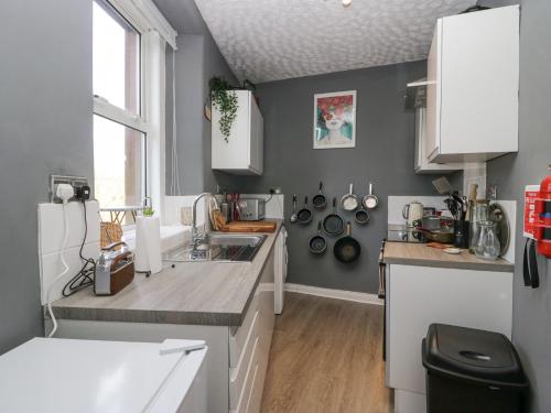 una cocina con armarios blancos y fregadero en Vale View en Egremont