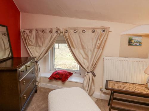 a bedroom with a window with a red pillow on a window sill at Vale View in Egremont