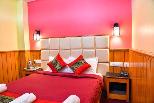 a bedroom with a large red bed with red pillows at Rufina Lachung Heritage in Lachung