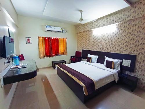 a hotel room with a bed and a television at Anjaneya Residency in Belgaum