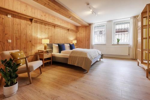 a bedroom with wooden walls and a bed and a chair at Fewos am Main mit Dachterrasse & Fahrradgarage - by homekeepers in Ochsenfurt
