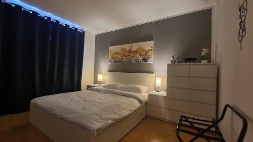 a bedroom with a bed and a dresser with two lamps at Cozy 2-Room Flat, for Vacation & Fair (Messe Düsseldorf) in Ratingen