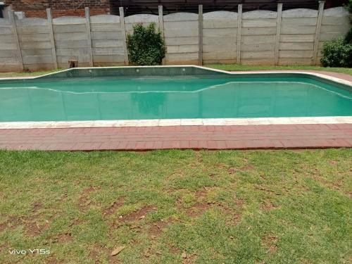 an empty swimming pool in a yard with grass at Bullez guest house in Mahikeng