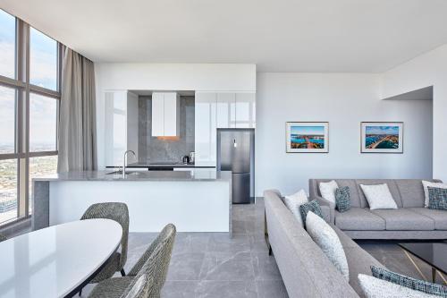 a kitchen and living room with a couch and a table at Meriton Suites George Street, Parramatta in Sydney