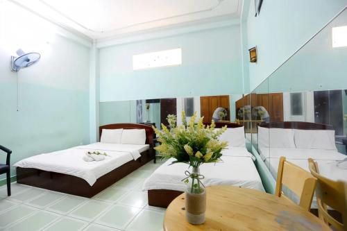 pokój z 2 łóżkami i stołem z kwiatami w obiekcie Hồng Lực Hotel HCM w Ho Chi Minh