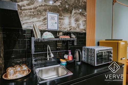 eine Küchentheke mit einer Spüle und einer Mikrowelle in der Unterkunft Ipoh Fumei 2R2B House 1 by Verve Pasir Pinji in Ipoh