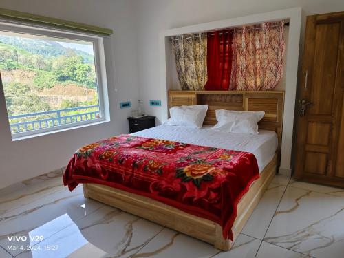 a bedroom with a bed with a red blanket and a window at Munnar Pavithra Riverview Homestay in Munnar