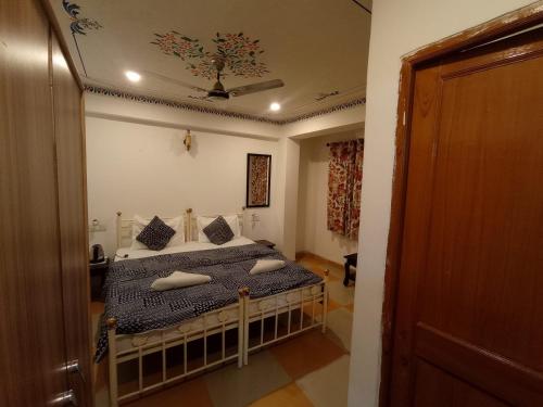 a bedroom with a bed with pillows and a ceiling at Little Peepal House in Udaipur