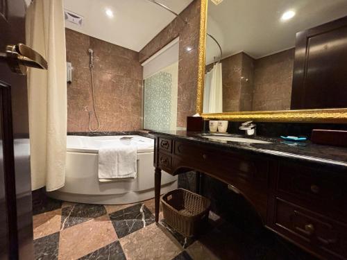 a bathroom with a tub and a sink and a mirror at Royal Seasons Hotel Taipei ‧ Nanjing W. in Taipei