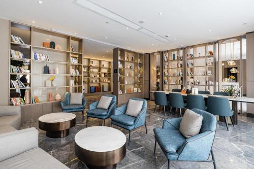 寧波的住宿－宁波外滩路劲新天地亚朵酒店，图书馆配有蓝色的桌椅和书架