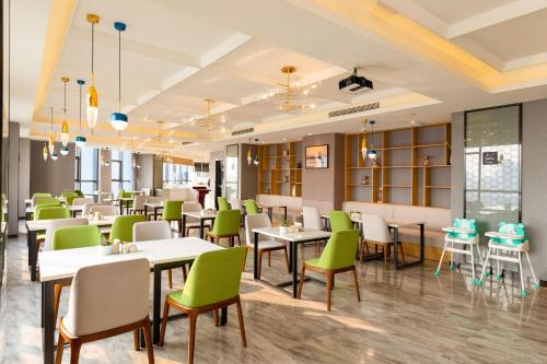 a dining room with tables and green chairs at Atour Hotel High Speed Railway Station Maoming in Maoming