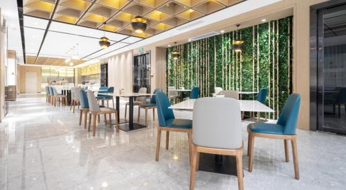 a dining room with tables and blue chairs at Atour Hotel Heyuan Wanlong in Heyuan