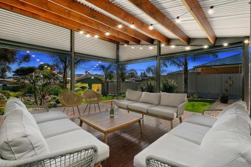 a patio with white couches and a table at Christies Garden - A Beachside Entertainer's Gem in Adelaide