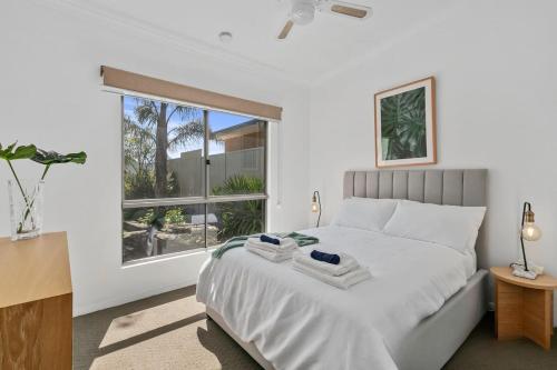 um quarto com uma cama branca e uma janela em Christies Garden - A Beachside Entertainer's Gem em Port Noarlunga
