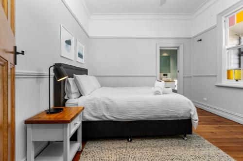 a white bedroom with a bed and a table at Pure Elegance in Cooks Hill in Newcastle