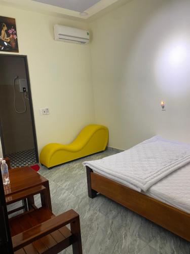 a bedroom with a bed and a yellow stool at SAIGON-PLEIKU HOTEL in Pleiku