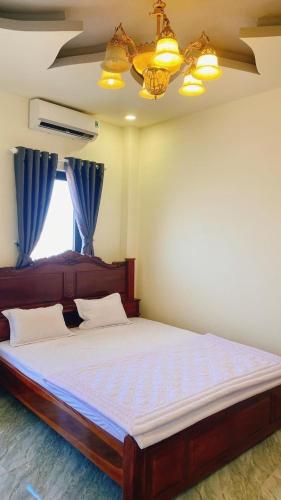 a bedroom with a large bed with blue curtains at SAIGON-PLEIKU HOTEL in Pleiku