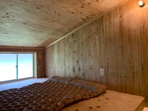 een groot bed in een kamer met houten wanden bij Shobara City, Hiroshimaの古民家の宿草叢 in Gōnotao