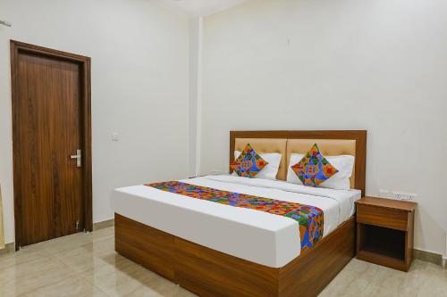 - une chambre avec un grand lit et une tête de lit en bois dans l'établissement FabHotel Grihum, à Indirapuram