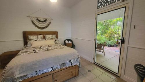 1 dormitorio con 1 cama y puerta corredera de cristal en Ribbonwood Bed & Breakfast, Emu Park Qld, en Emu Park