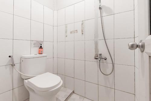 a white bathroom with a shower and a toilet at RedDoorz near Botani Square Mall in Bogor