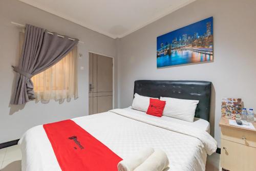 um quarto com uma cama grande e um cobertor vermelho em RedDoorz near Botani Square Mall em Bogor