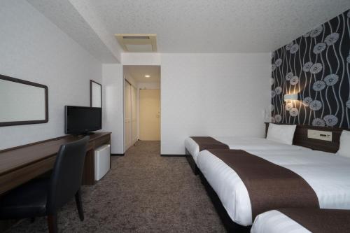a hotel room with two beds and a flat screen tv at Hotel Centmain Nagoya in Nagoya