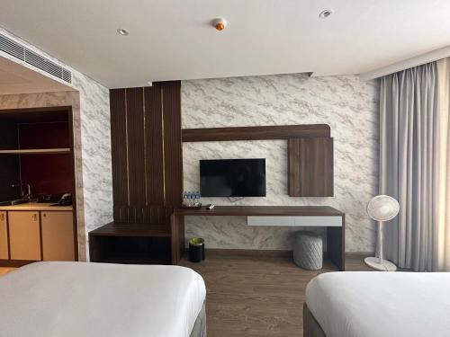 a hotel room with two beds and a television at Apec Mandala Mui Ne Phan Thiet in Ấp Long Sơn