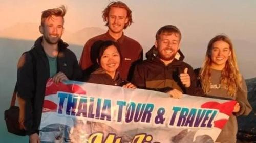 un grupo de personas posando para una foto sosteniendo un cartel en Thalia Homestay, en Banyuwangi