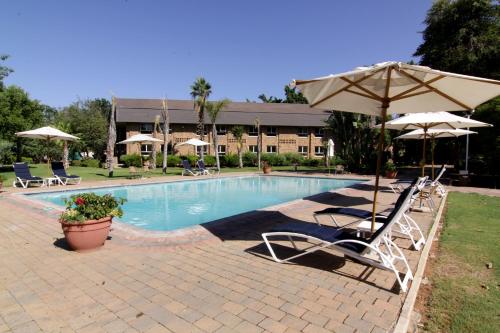 a pool with two lawn chairs and an umbrella at Cresta Lodge Gaborone in Gaborone