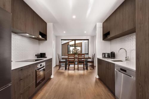 a kitchen with wooden cabinets and a dining room at Stylish Brand New Sunny 3Bdrm 3Bth garage sleeps 6 in Christchurch