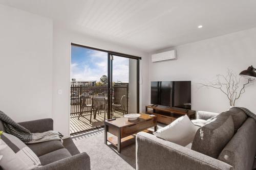 a living room with two couches and a television at Stylish Brand New Sunny 3Bdrm 3Bth garage sleeps 6 in Christchurch