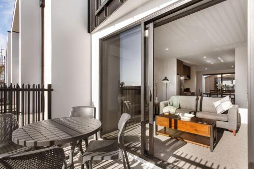 a balcony with a couch and a table and chairs at Stylish Brand New Sunny 3Bdrm 3Bth garage sleeps 6 in Christchurch