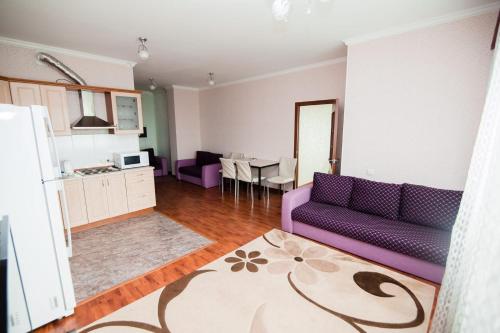 een woonkamer met een paarse bank en een keuken bij Центр города Байтерек in Astana