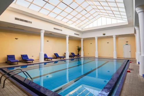 a swimming pool with blue chairs and a skylight at Palma Beach Resort & Spa in Umm Al Quwain