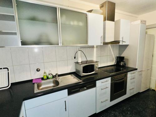 uma cozinha com armários brancos, um lavatório e um micro-ondas em TULUM APARTMENTS - STUTTGART CITY em Stuttgart