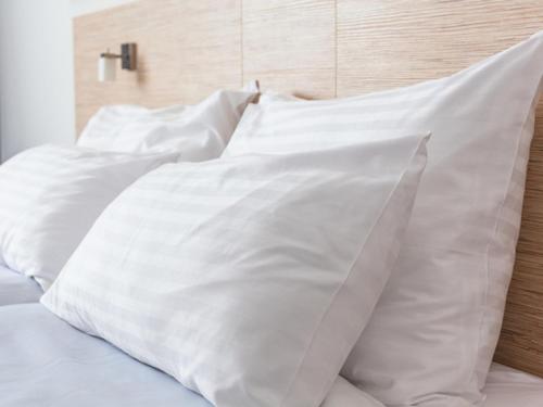 a pile of white pillows on a bed at Hotel Centmain Nagoya in Nagoya