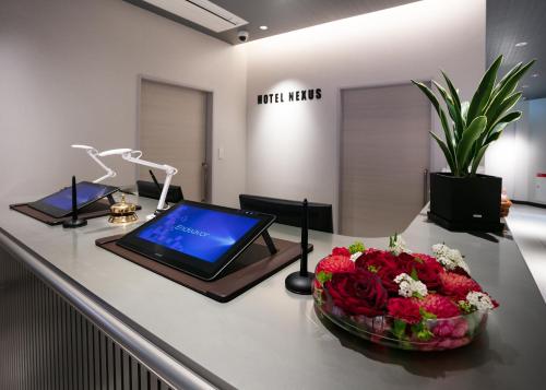 a laptop computer on a counter with a bouquet of flowers at HOTEL NEXUS Hakata Sanno in Fukuoka