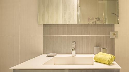 La salle de bains est pourvue d'un lavabo et d'une serviette jaune. dans l'établissement Le Balcon Troyen - Proche Hypercentre - 4 Pers., à Troyes