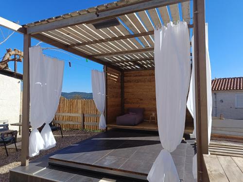 eine hölzerne Pergola mit weißen Vorhängen auf einer Terrasse in der Unterkunft Agios Ioannis Stone Cottage with Private Heated Pool & Hydro-massage in Áyios Ioánnis