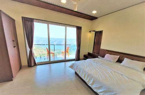 a bedroom with a bed and a large window at Vinayaka Holiday Homes - Infinity Pool and Breathtaking Valley View in Panchgani