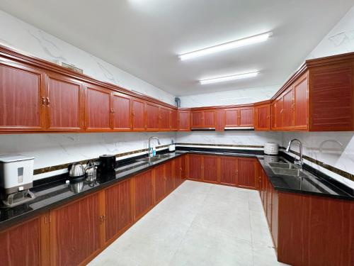 una cocina con armarios de madera y encimeras negras en Phượng Hoàng villa 13 phòng ngủ - bể bơi, en Ha Long