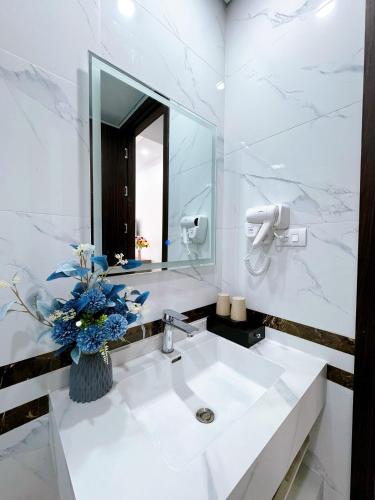 a white bathroom with a sink and a mirror at Phượng Hoàng villa - bể bơi, phòng karaoke, sân Pickleball, xe địa hình, xe đạp đôi in Ha Long