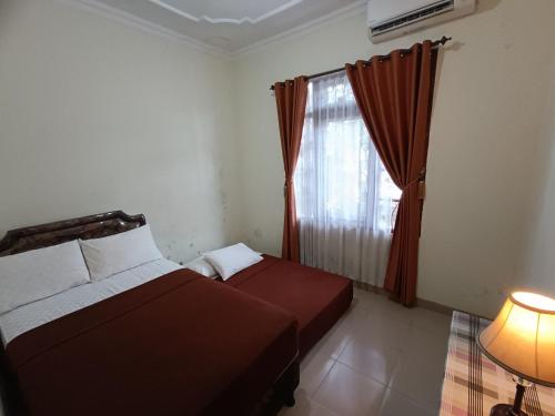 ジョグジャカルタにあるNdalem Cemara Homestayのベッドルーム1室(ベッド2台、窓、ランプ付)