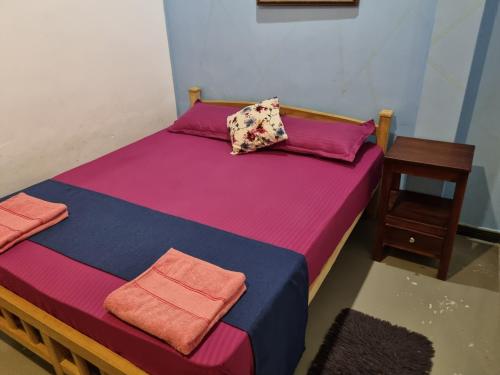 a bed with colorful sheets and pillows and a table at River Front Villa in Wadduwa