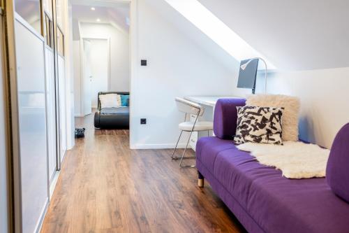 a living room with a purple couch and a desk at Celje Center Apartment in Celje