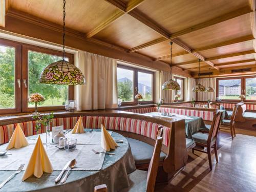 a dining room with tables and chairs and windows at Hotel Neuwirt in Kirchdorf in Tirol