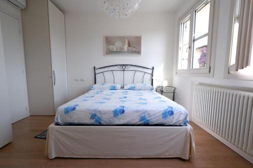 Schlafzimmer mit einem Bett mit einer blauen und weißen Bettdecke in der Unterkunft GARDA BLUE HOME - Piscina, Solarium e Box in Toscolano-Maderno
